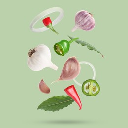 Image of Different spices falling on light green background