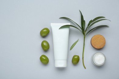 Photo of Cosmetic products with olive essential oil on light grey background, flat lay
