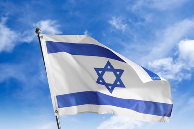 National flag of Israel against blue sky with clouds