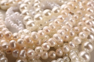 Photo of Elegant pearl necklaces as background, closeup view