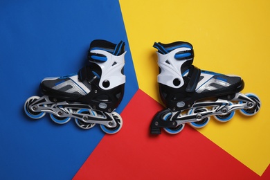 Photo of Pair of inline roller skates on color background, top view