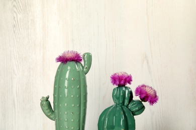 Photo of Trendy cactus shaped ceramic vases with flowers on wooden background