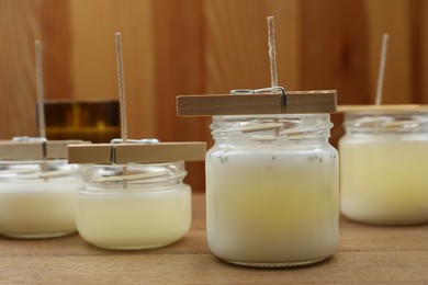 Photo of Glass jars with wax on wooden table, space for text. Handmade candles