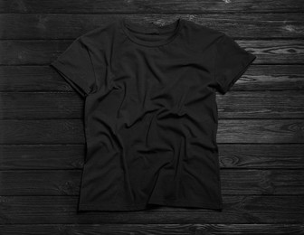 Photo of Stylish t-shirt on black wooden background, top view