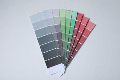 Photo of Color paint chips on light background, top view