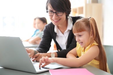 Photo of Female teacher helping child with assignment at school