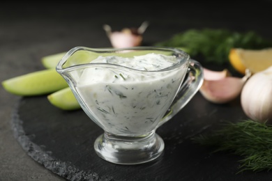 Photo of Tzatziki cucumber sauce in glass pitcher with ingredients on table
