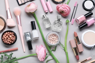 Photo of Flat lay composition with different makeup products and beautiful spring flowers on gray background
