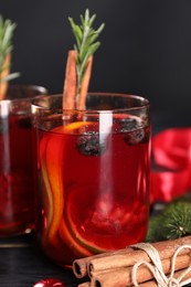 Photo of Aromatic Sangria drink in glasses, ingredients and Christmas decor on black wooden table, closeup