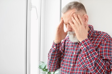 Photo of Mature man suffering from headache at home