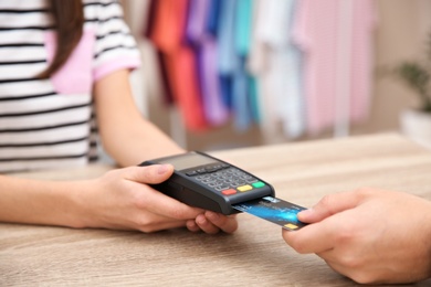 Photo of Man using terminal for credit card payment in shop, closeup