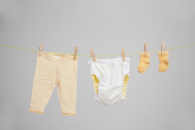 Photo of Baby clothes hanging on washing line against gray background