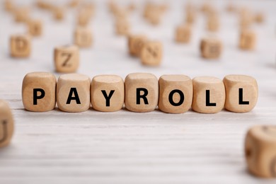Photo of Word Payroll made of cubes on white wooden table