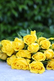 Photo of Beautiful bouquet of yellow roses on light table outdoors. Space for text