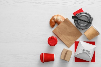 Photo of Flat lay composition with paper bag and different takeaway items on wooden background. Space for design