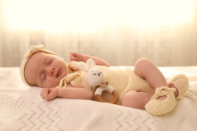Photo of Adorable newborn baby with toy on knitted plaid in room