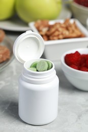 Photo of Bottle of pills near foodstuff on grey table. Prebiotic supplements