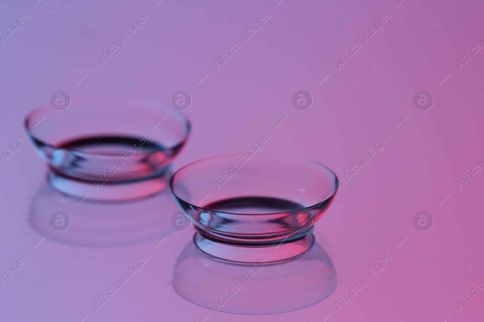 Photo of Pair of contact lenses on mirror surface, closeup. Space for text