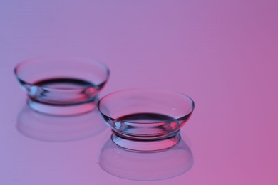 Photo of Pair of contact lenses on mirror surface, closeup. Space for text