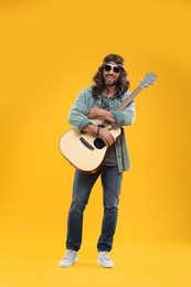 Photo of Stylish hippie man with guitar on orange background