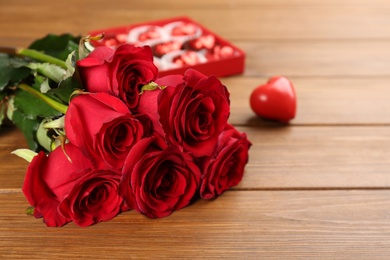 Photo of Beautiful red roses on wooden table, space for text. Valentine's Day celebration