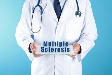 Image of Multiple Sclerosis concept. Doctor holding modern tablet on turquoise background, closeup