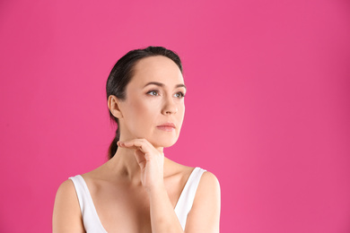 Portrait of beautiful mature woman on pink background. Space for text