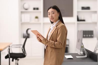 Photo of Portrait of smiling businesswoman with tablet in office