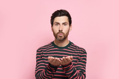 Photo of Handsome man blowing kiss on pink background
