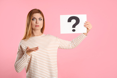 Photo of Confused woman holding question mark sign on pink background