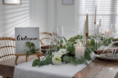 Photo of Festive table setting with floral decor and Welcome sign indoors