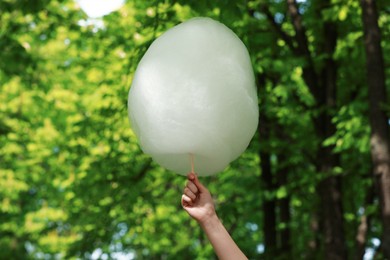 Photo of Woman holding sweet cotton candy outdoors, closeup
