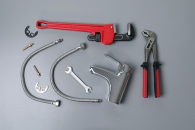 Photo of Parts of water tap and wrenches on grey background, flat lay