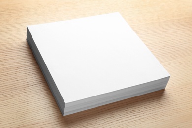 Photo of Stack of blank paper sheets for brochure on wooden background. Mock up
