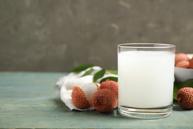 Photo of Fresh lychee juice and fruits on blue wooden table. Space for text