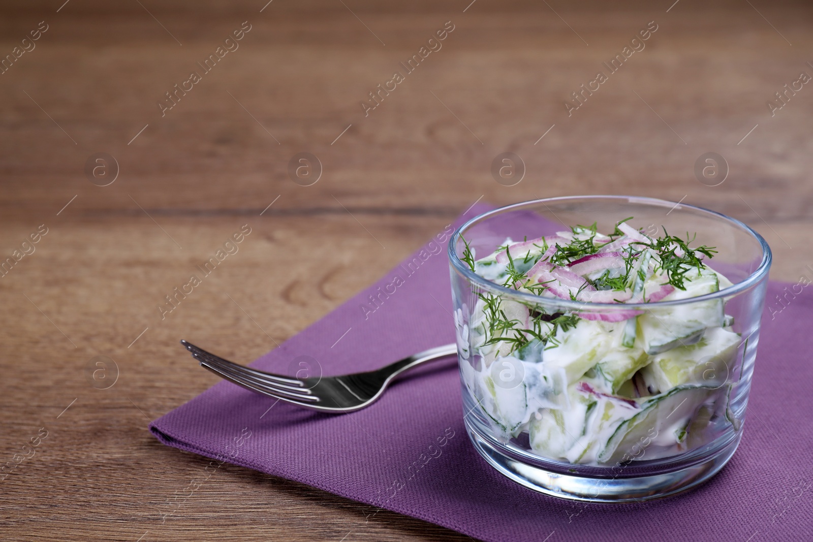 Glass bowl of vegetarian salad with cucumber and onion served on table. Space for text Photo of Glass bowl of vegetarian salad with cucumber and onion served on table. Space for text