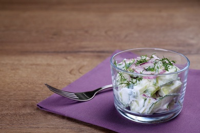 Photo of Glass bowl of vegetarian salad with cucumber and onion served on table. Space for text