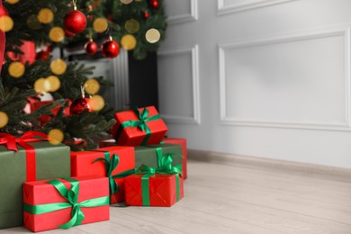 Photo of Beautifully wrapped gift boxes under Christmas tree indoors