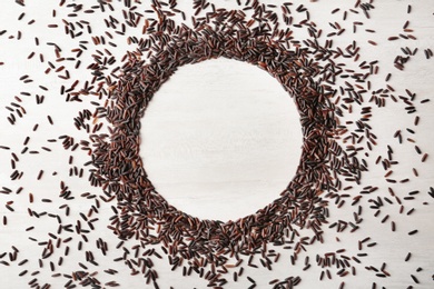 Photo of Round frame made with black rice on white wooden background, top view. Space for text