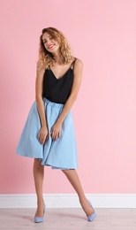 Photo of Young woman with beautiful long legs in stylish outfit near color wall