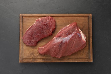 Photo of Pieces of raw beef meat on black table, top view