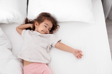 Photo of Cute little girl sleeping on cozy bed, view from above