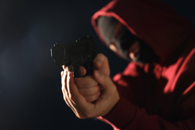 Man in mask holding gun on dark background, focus on hands