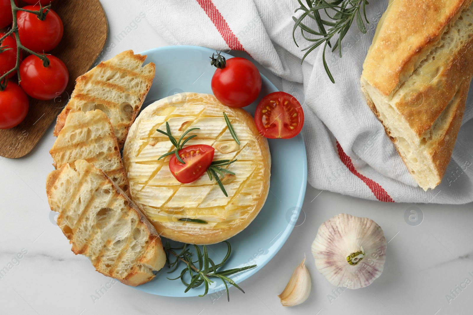 Photo of Tasty baked brie cheese served on white marble table, flat lay