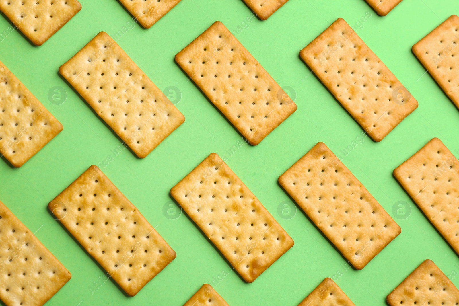 Photo of Delicious crackers on light green background, flat lay