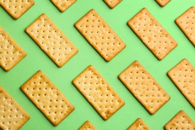 Delicious crackers on light green background, flat lay