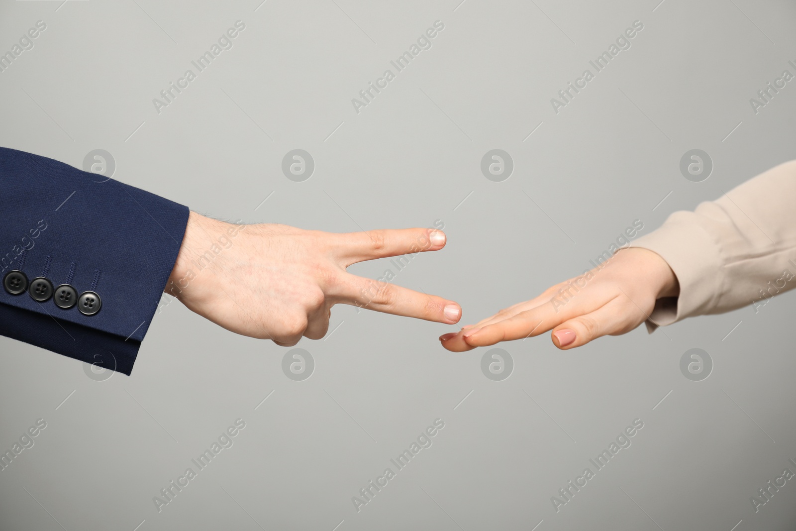 Photo of People playing rock, paper and scissors on grey background, closeup