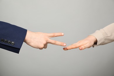 People playing rock, paper and scissors on grey background, closeup