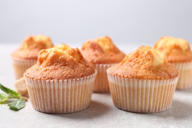 Delicious sweet muffins on light grey textured table, closeup