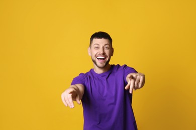 Photo of Handsome man laughing on yellow background. Funny joke